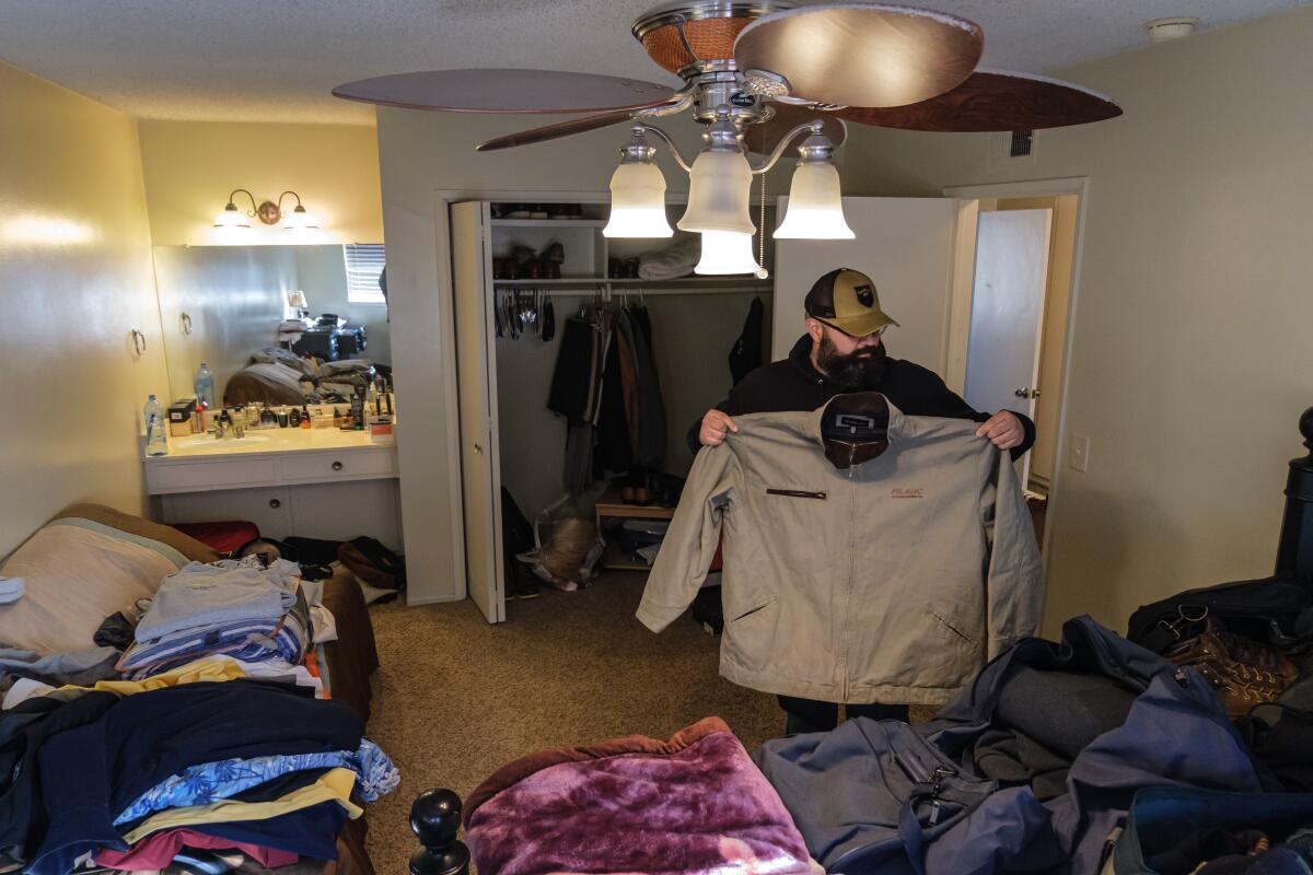 A man packs his clothes in a room. 