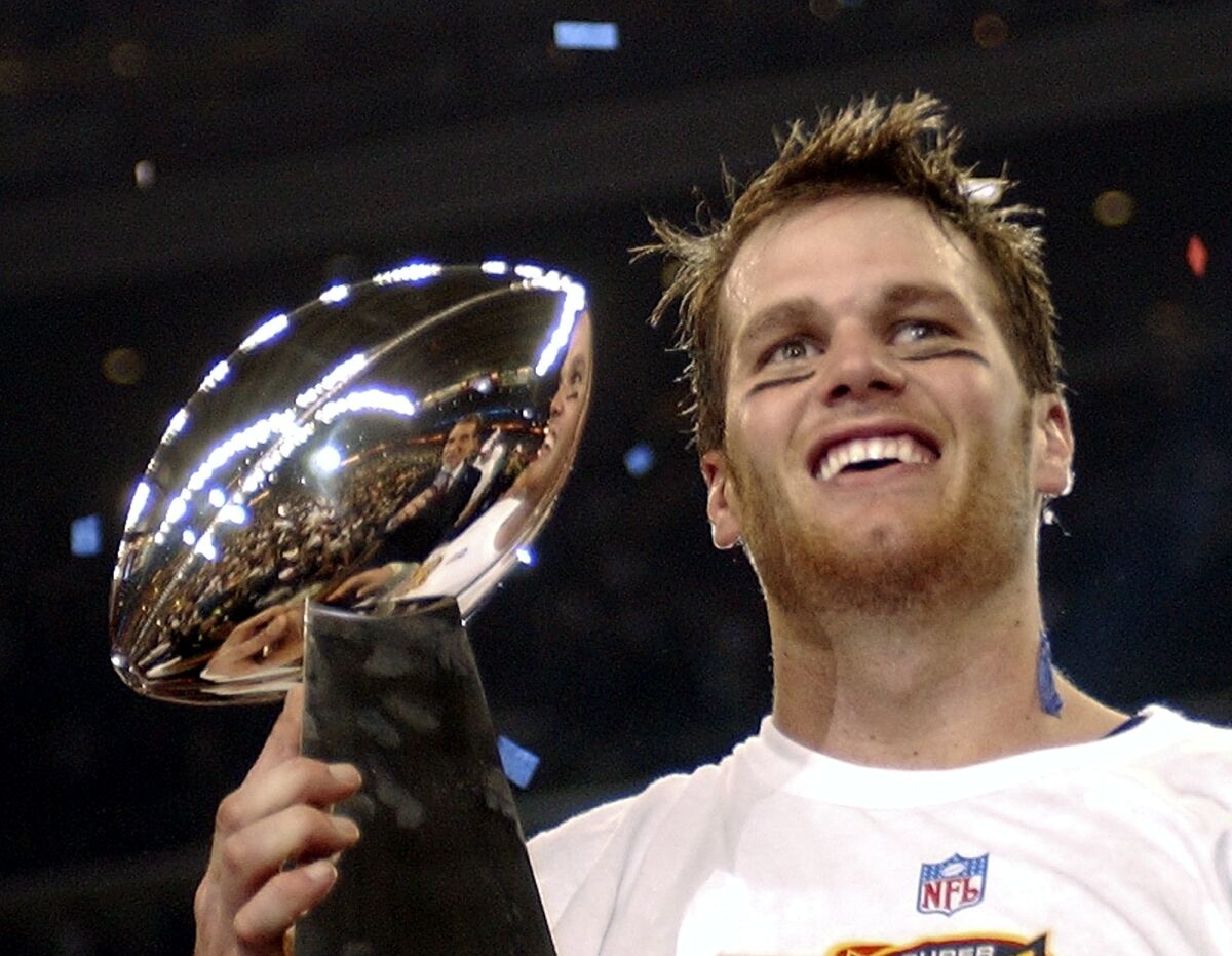 FILE - New England Patriots quarterback Tom Brady holds the Vince Lombardi Trophy after the Patriots beat the Carolina Panthers 32-29 in Super Bowl XXXVIII in Houston, Feb. 1, 2004. Despite reports that he is retiring, Brady has told the Tampa Bay Buccaneers he hasn't made up his mind, two people familiar with the details told The Associated Press, Saturday, Jan. 29, 2022. (AP Photo/Dave Martin, File)