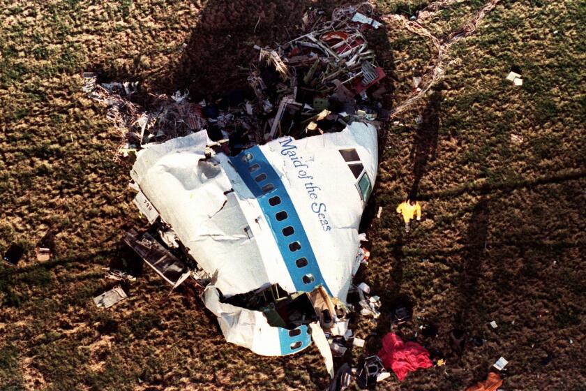 FILE - In this Dec. 22, 1988, file photo police and investigators look at what remains of the nose of Pan Am 103 in a field in Lockerbie, Scotland. The Justice Department expects to unseal charges in the coming days in connection with the 1988 bombing of a Pan Am jet that exploded over Lockerbie, Scotland, killing 270 people, according to a person familiar with the case. (AP Photo/Martin Cleaver, File)