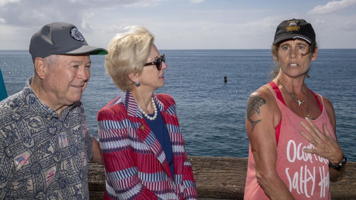 Rep. Dana Rohrabacher, left, and Newport Beach City Council Member Diane Dixon, listen to Maria Korcsmaros, right, who was attacked by a great white shark in 2016, talk about the importance of using shark-detecting technology.