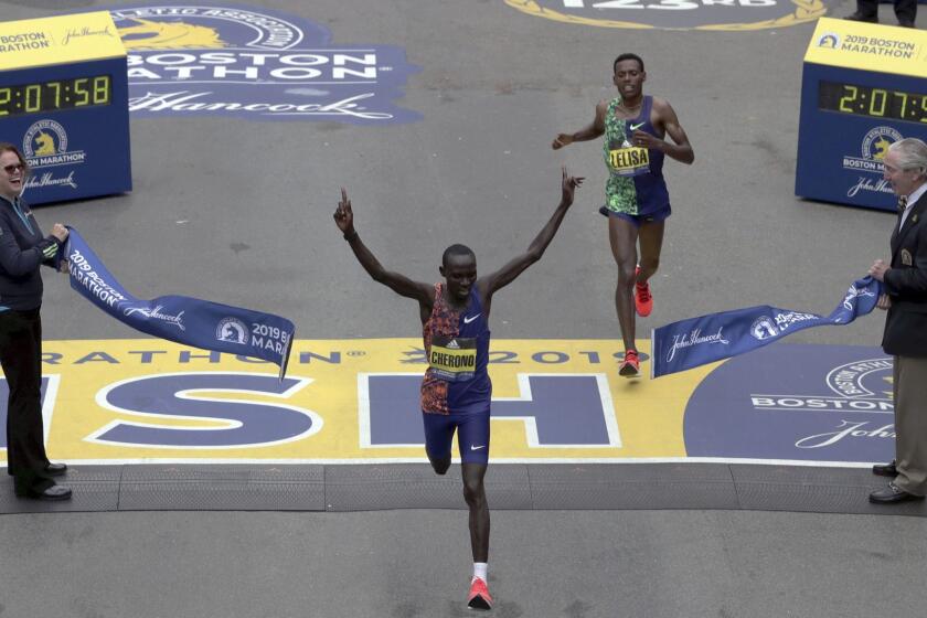 Lawrence Cherono, of Kenya, breaks the tape to win the 123rd Boston Marathon in front of Lelisa Desisa, of Ethiopia, right, on Monday, April 15, 2019, in Boston. (AP Photo/Charles Krupa)