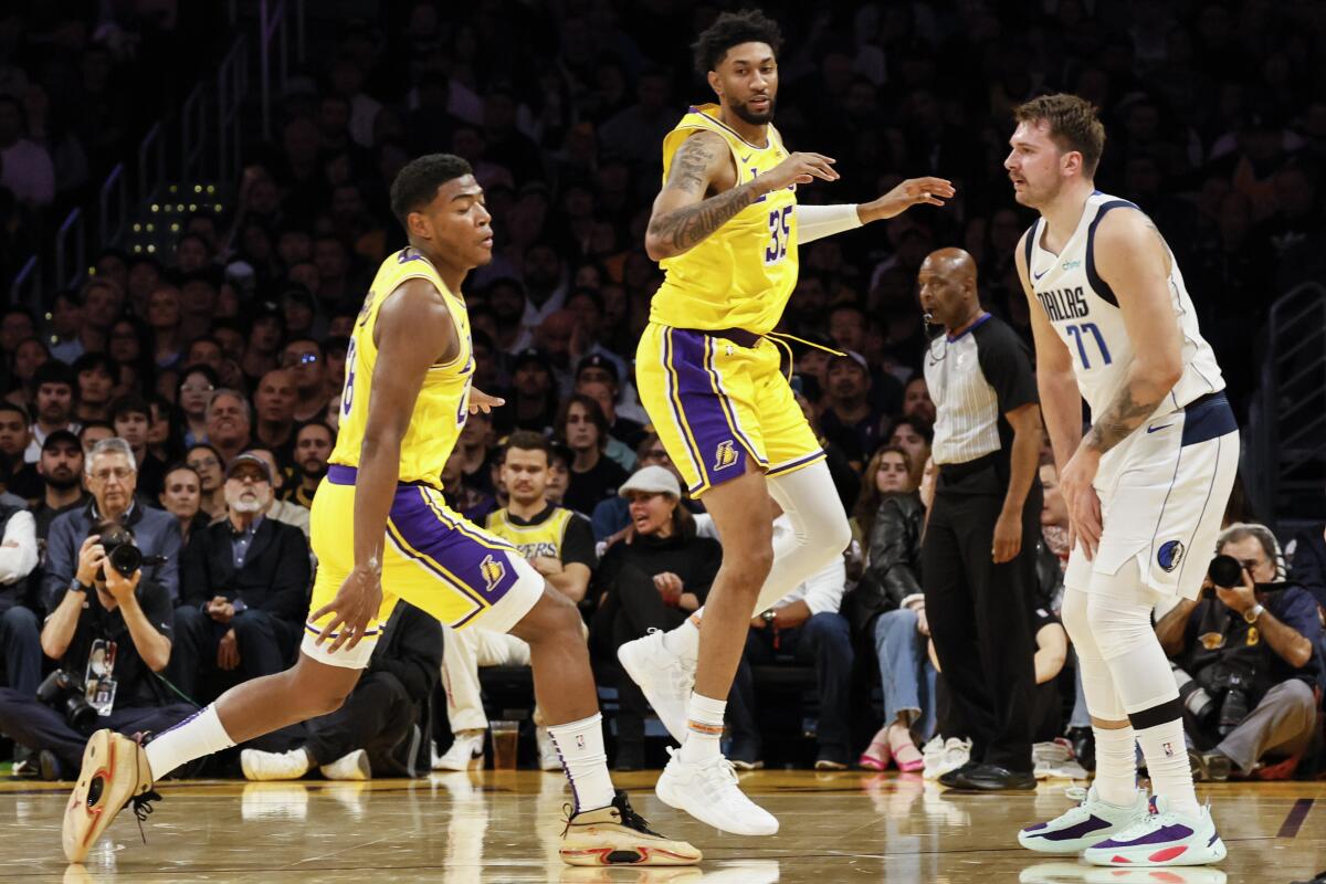 Lakers forward Christian Wood attempts to cover Mavericks guard Luka Doncic while Anthony Davis looks on