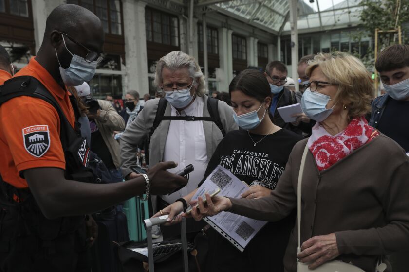 A security officer checks passengers' health passes at the Gare de Lyon train station in Paris, Monday Aug.9, 2021. Starting today, the pass will be required in France to access cafes, restaurants, long-distance travel and, in some cases, hospitals. It was already in place for cultural and recreational venues, including cinemas, concert halls, sports arenas and theme parks with a capacity for more than 50 people. (AP Photo/Adrienne Surprenant)