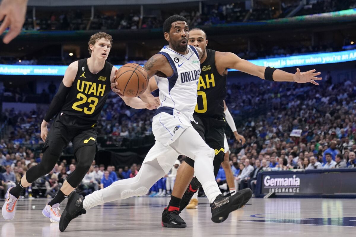Dallas Mavericks guard Kyrie Irving, front, drives to the basket past Utah Jazz forward Lauri Markkanen (23) and Talen Horton-Tucker (0) in the first half of an NBA basketball game, Tuesday, March 7, 2023, in Dallas. (AP Photo/Tony Gutierrez)
