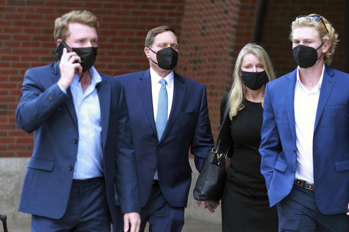 John Wilson, second left, holds his wife's hand, second right, as he leaves the John Joseph Moakley Federal Courthouse after the first day of his trial in the college admissions scandal, Monday, Sept.13, 2021, in Boston. (AP Photo/Stew Milne)