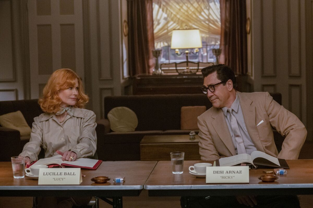 Nicole Kidman and Javier Bardem exchange glances at a table in "Being the Ricardos."