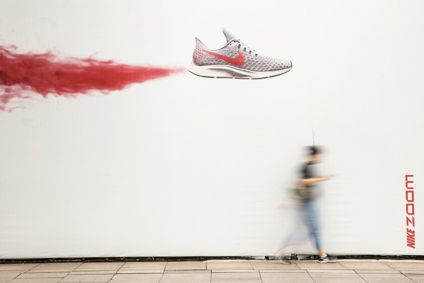 A pedestrian walks past Nike advertising in Shanghai, China, on July 6, 2018. This week, Nike became the latest example of companies unexpectedly raising wages when it said in a memo to employees that the company would adjust the pay of about 10 percent of its 74,000 workers and revamp its bonus system.