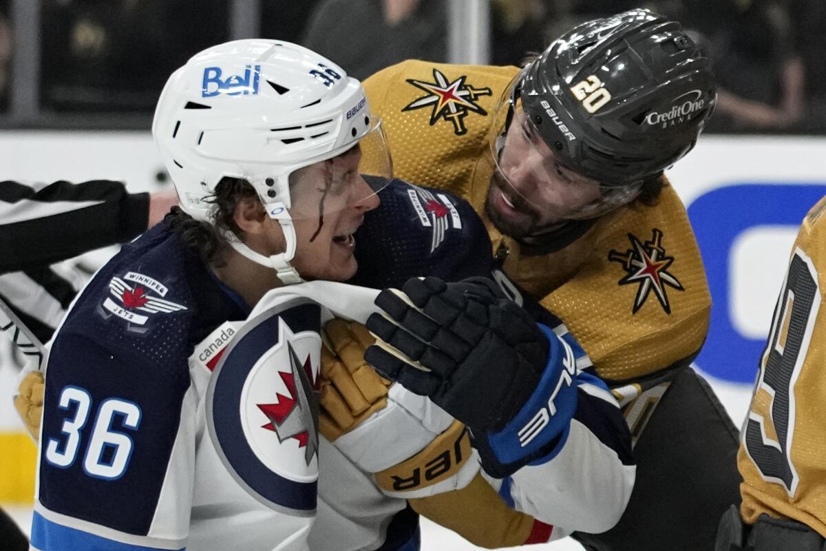 Vegas' Chandler Stephenson helps Winnipeg's Morgan Barron, who is bleeding after he cut his face on a skate