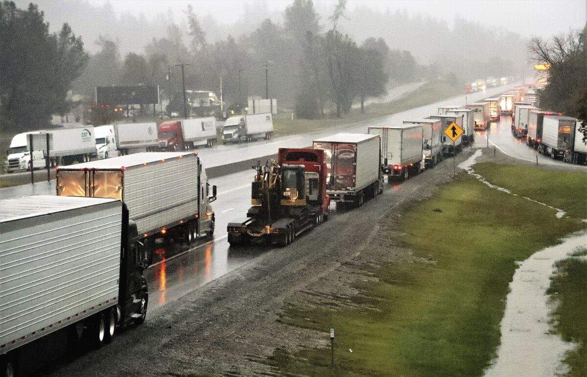 Dozens of semi-trucks sit parked along northbound Interstate 5 at Mountain Gate about 10 miles north of Redding, Calif., on Wednesday, Dec. 15, 2021. Heavy snow, blizzard conditions and stuck vehicles have prompted authorities to impose a shutdown of a portion of the West Coast's major interstate that links California with Oregon. California officials Wednesday afternoon closed Interstate 5 north of the city of Redding as the latest of back-to-back storms slammed the region. (Mike Chapman/The Record Searchlight via AP)