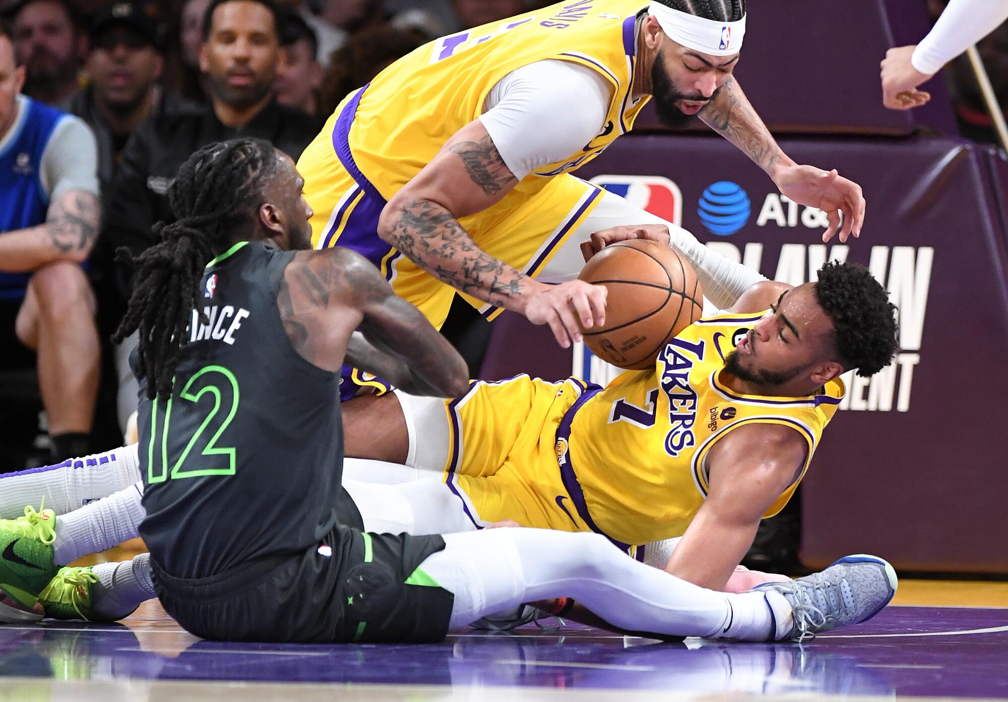 Lakers Troy Brown Jr., right, and Anthony Davis, top, battle for a loose ball with Timberwolves forward Taurean Prince.