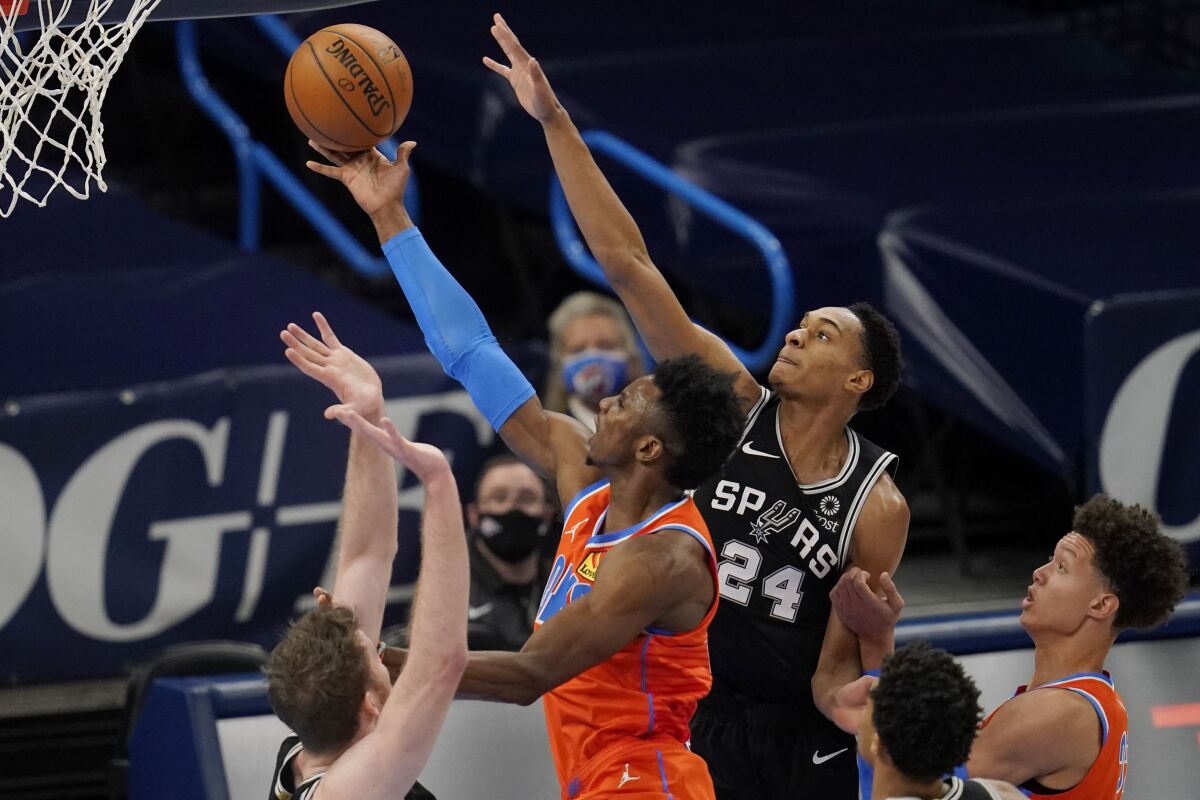 Oklahoma City Thunder guard Hamidou Diallo, center, goes to the basket between San Antonio Spurs center Jakob Poeltl, left, and guard Devin Vassell (24) during the first half of an NBA basketball game Tuesday, Jan. 12, 2021, in Oklahoma City. (AP Photo/Sue Ogrocki)