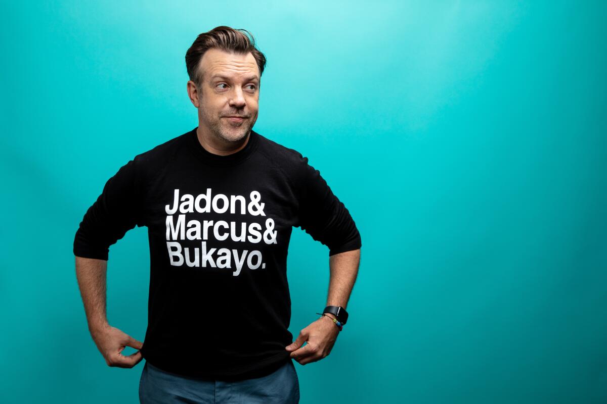 A man wears a black shirt reading "Jadon & Marcus & Bukayo"