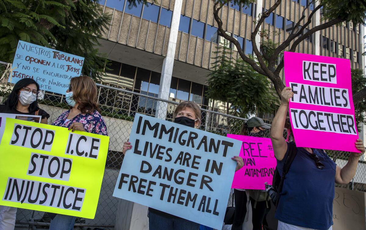 Family members of detainees at the Adelanto Immigration Detention Center hold signs in front of the Federal Building