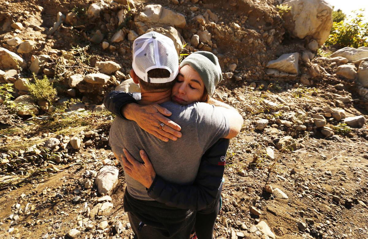 Alison Hardy hugs David Scharps, who survived staying in this home during the floods and fire as they hike among the exposed boulders at Cold Spring Creek. (Al Seib / Los Angeles Times)