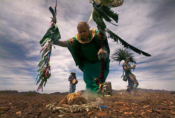 Estrella Newman, 76, center, from Mexico City, drummer Jesus Figuera, left, and Aztec dancer Netze Cuauhtemoc, right, perform a sacred dance around burning sage during a ritual cleansing of the grounds near several giant geoglyphs in the desert near Blythe, Calif., in March. The dancers and others are opposed to the construction of a nearby solar energy facility that could endanger the carvings. See full story