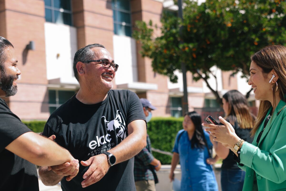 A male college student mingles on campus with two other students. 