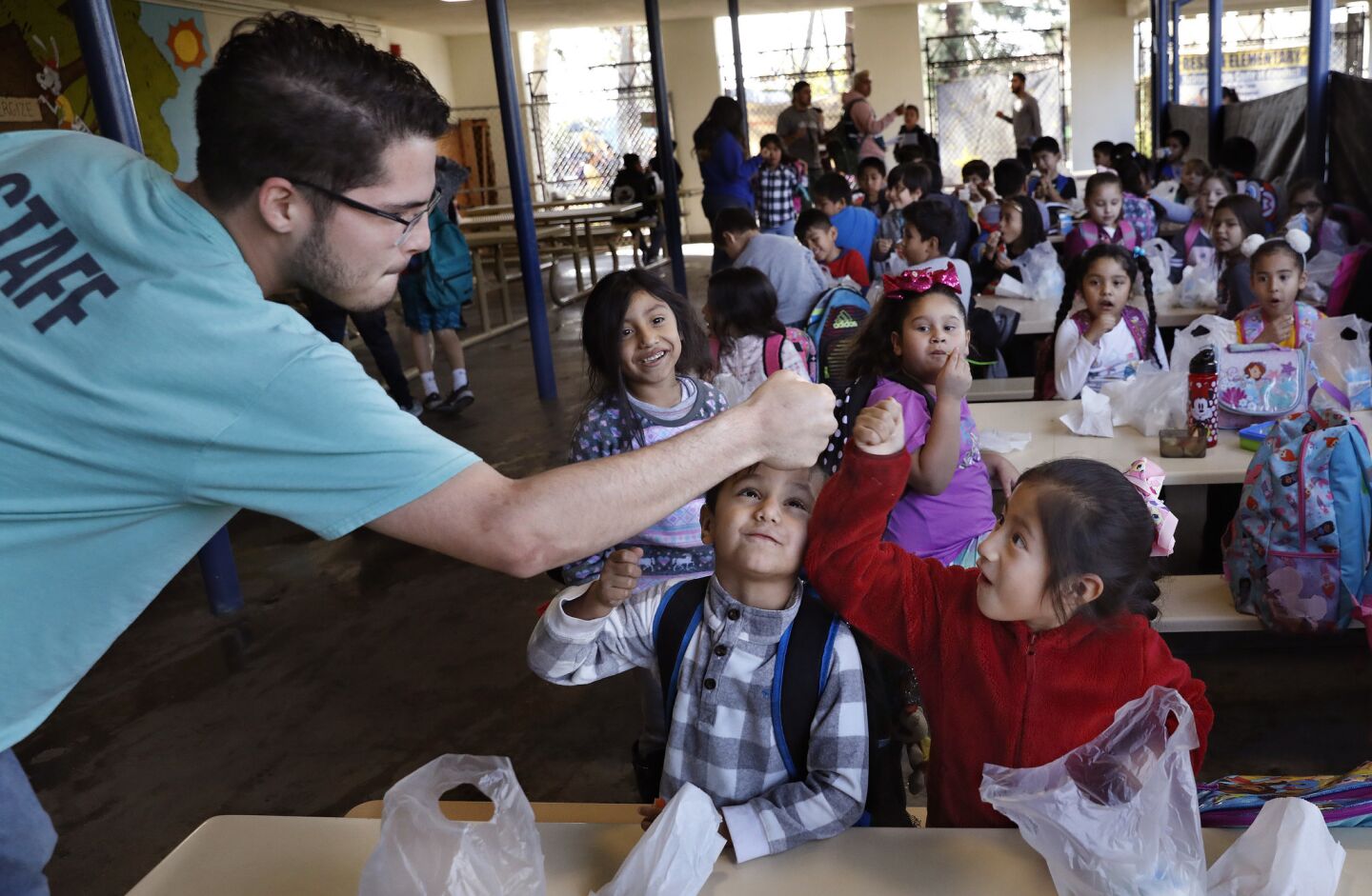 Michael Rothhammer gives a fist bump to Jayden Arriaga, center, and Emely Herrera, kindergartners in an after school program at Reseda Elementary School.