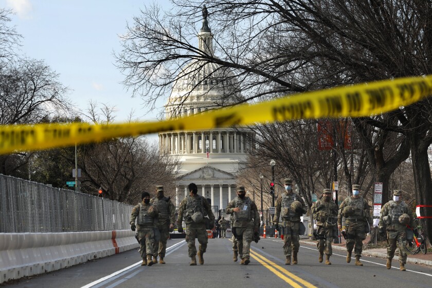 Troops walk away from the east side of the U.S. Capitol.