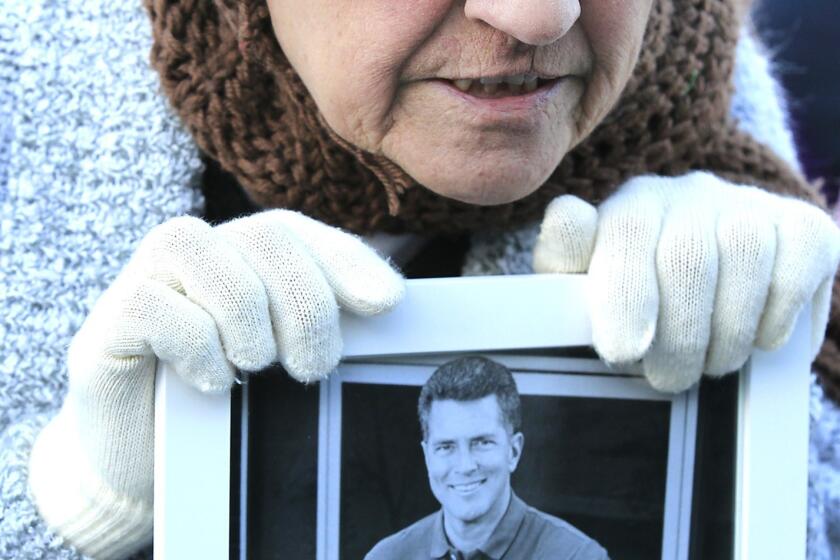 Mary Cardona holds a photo of Huell Howser as she and hundreds of others gather to celebrate and remember the life of television host Huell Howser during a memorial tribute at Griffith Observatory on Tuesday. [For the record, Jan. 19, 5:19 p.m.: An earlier version of this caption misidentified Mary Cardona as Mary Cardinella.]