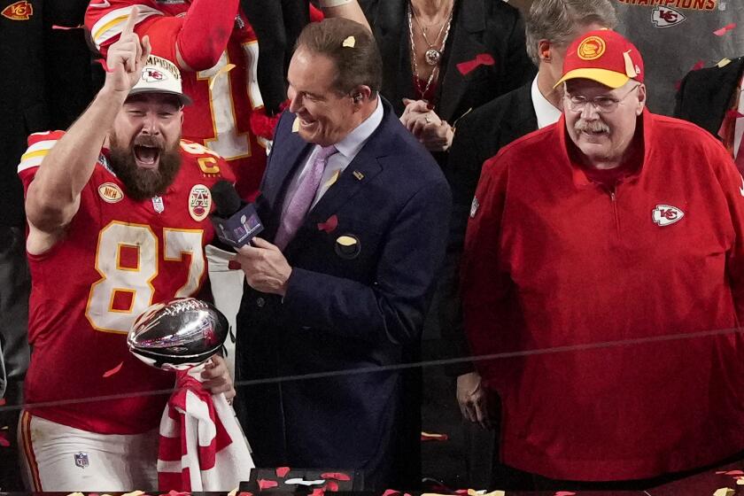 Travis Kelce smiles and yells while holding the Vince Lombardi Trophy and is interviewed by Jim Nantz.