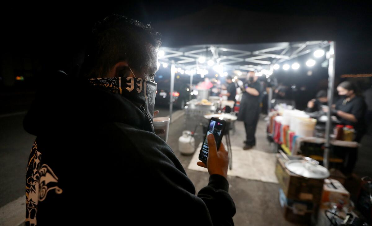 Joe Bautista shoots video to show his Instagram followers a scene of food vendors in La Puente.