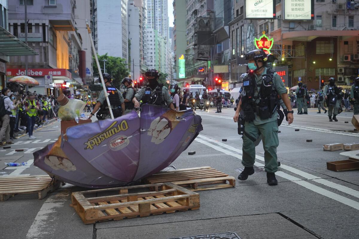 Police inspect a makeshift roadblock set up by protesters in Hong Kong