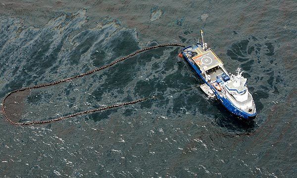 Off the Louisiana coast in the Gulf of Mexico, a boat tries to contain oil spilled when the Deepwater Horizon oil rig exploded and collapsed this week