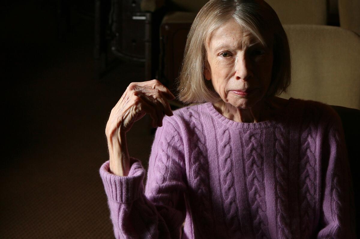 A woman posing in a cable-knit purple sweater.