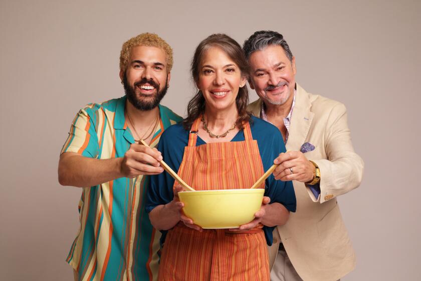 Joel Perez, left, Melinda Lopez and Al Rodrigo hold a pot of black beans in the Old Globe's "Stir."