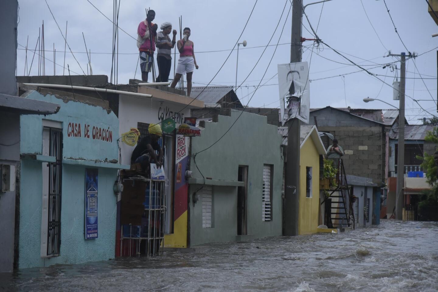 People look down on a flooded street from a roof in Santiago de los Caballeros, Dominican Republic, September 7, 2017. More than 5,500 people have been evacuated in the Dominican Republic because of the powerful category 5 hurricane Irma, which is causing rains and strong winds in the northeast of the country after leaving Puerto Rico.