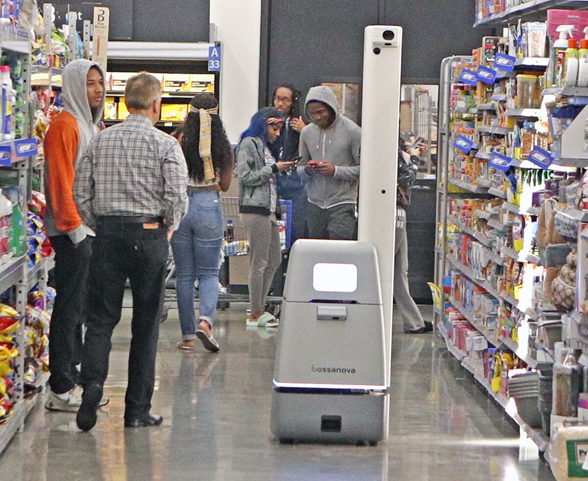 Walmart shoppers gather near a shelf-scanning robot