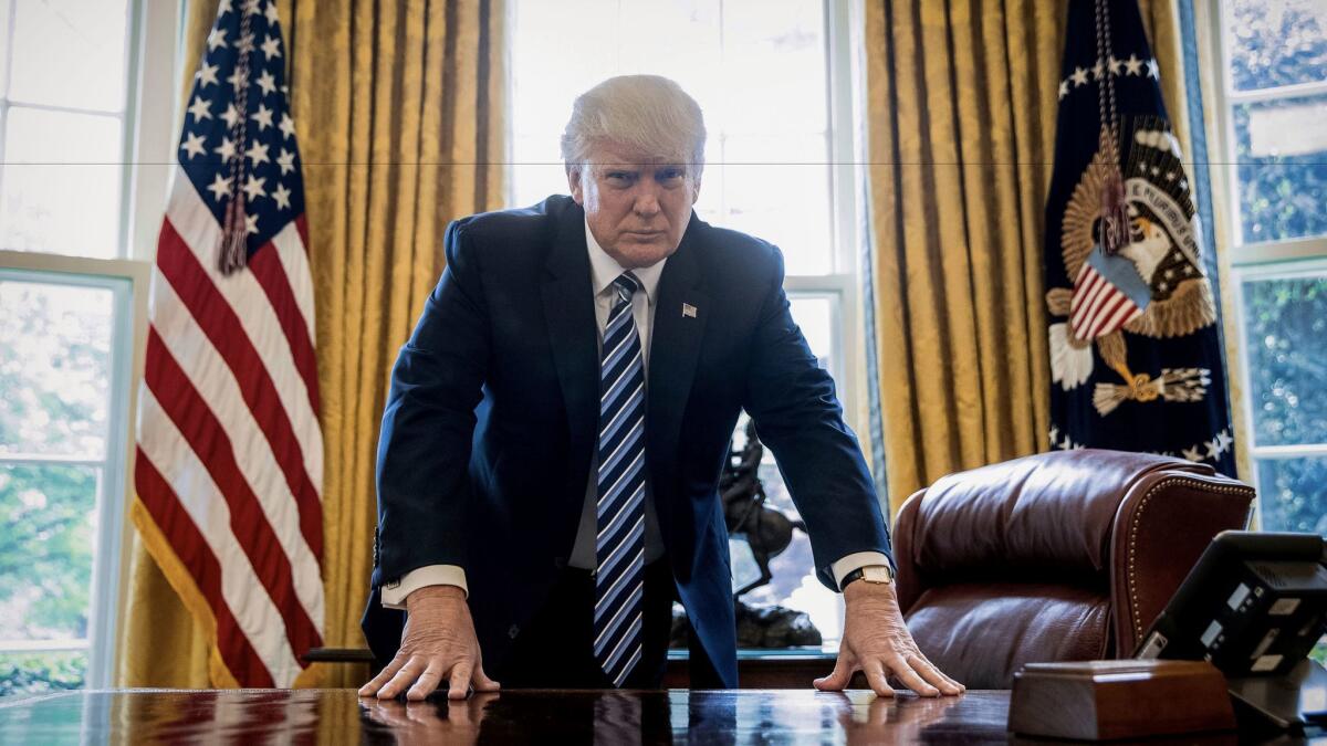 President Donald Trump poses for a portrait in the Oval Office.
