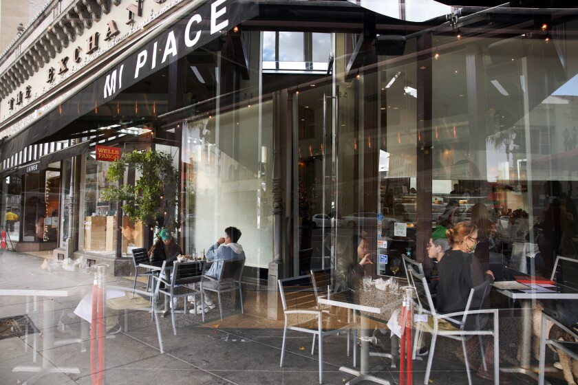 In a double exposure, layers of people sit at the sidewalk tables at Mi Place.