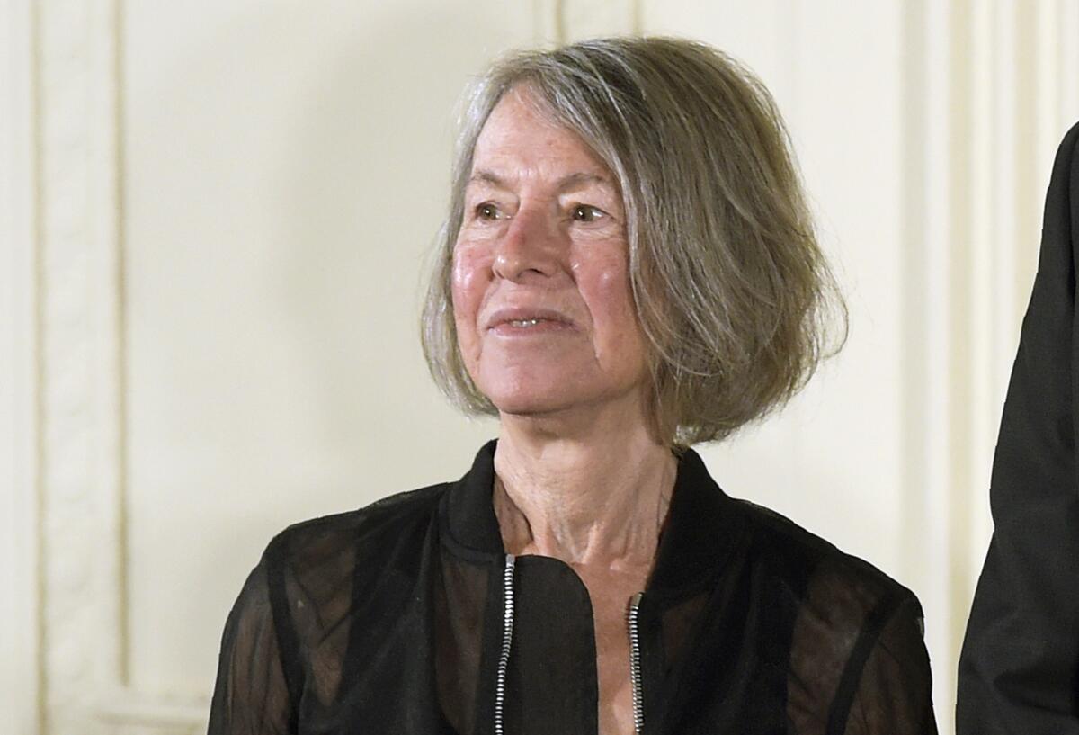 Louise Glück, with short gray hair, looks to the side while wearing a dark jacket