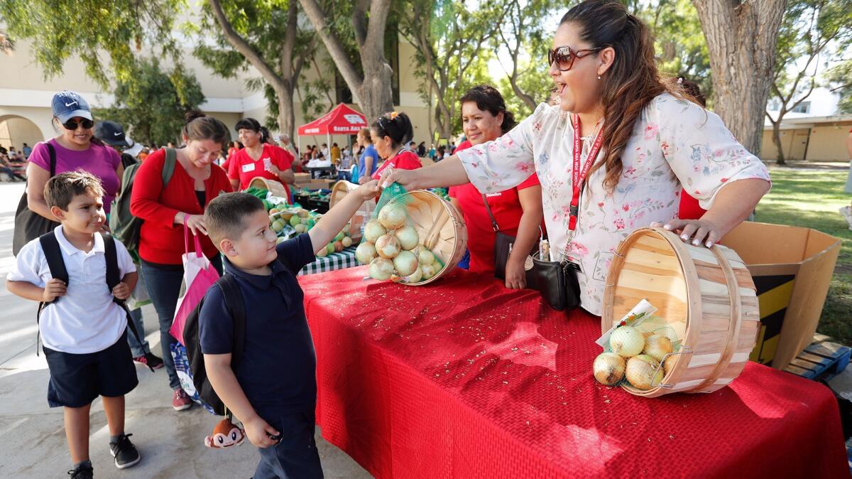 Guillermo Mendoza, 5, gets a bag of onions during a farmers market from Second Harvest Food Bank of Orange County at Santa Ana High School.