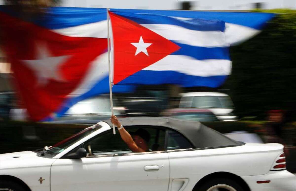 A motorist waves a Cuban flag in Miami's Little Havana neighborhood. Recent polls have shown that Americans are more open to normalizing relations with Cuba.