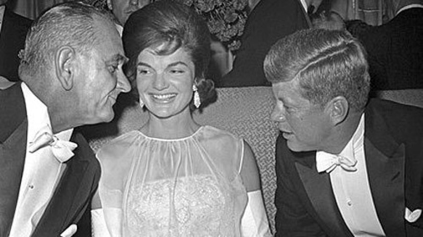 Vice President Lyndon B. Johnson chats with President Kennedy and First Lady Jacqueline Kennedy at the inaugural ball in 1961. Kennedy's gowns were inspired by French haute couture but made in America.