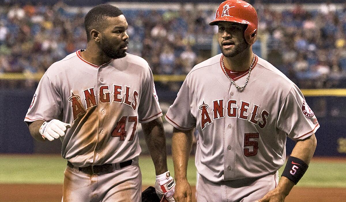 Angels second baseman Howie Kendrick (47) and first baseman Albert Pujols (5) head to the dugout after Pujols scored on Kendrick's run-scoring single in the first inning against the Rays on Sunday. Kendrick was put out when the relay throw was cut off.