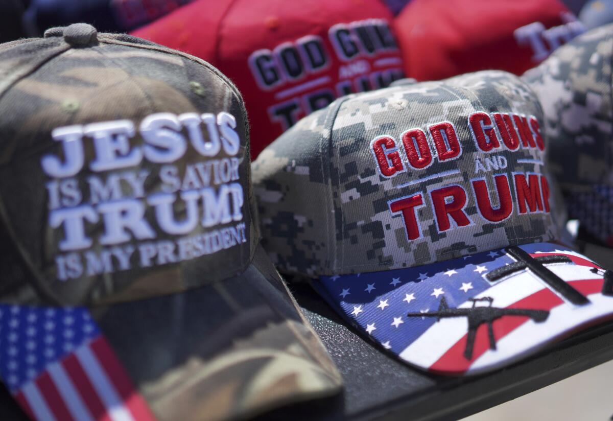Christian-themed pro-Trump hats are sold at a campaign rally for the former president in Ohio on March 16. 