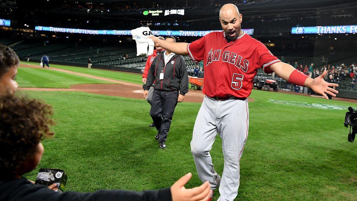 The Angels' Albert Pujols prepares to hug his children after getting his 3,000th hit Friday in Seattle.