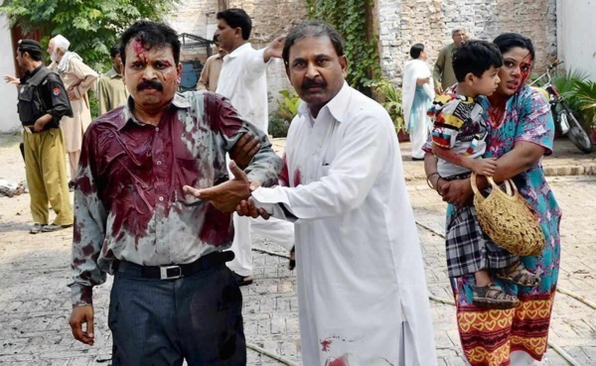 A Pakistani man helps one of the injured after two suicide bombers blew themselves up just after services at a church in Peshawar.