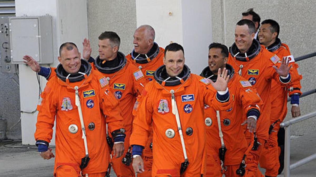 The Discovery crew members wave as they leave the crew quarters at Kennedy Space Center in Florida.