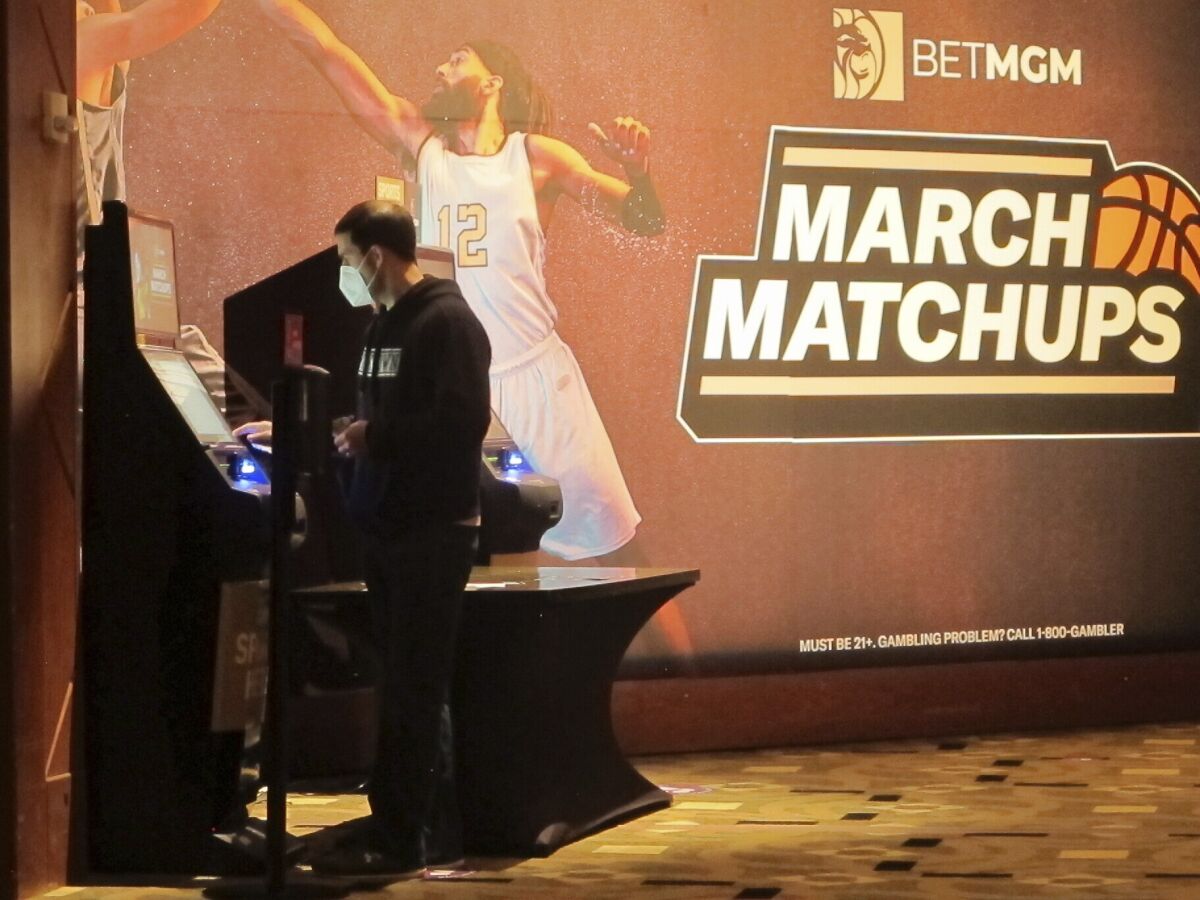 A man makes a bet at a kiosk in the Borgata casino in Atlantic City NJ on March 19, 2021 at the start of the March Madness college basketball tournament. On March 28, 2023, the American Gaming Association issued a new marketing code prohibiting sports books from partnering with colleges to promote sports wagering, banning payments to college and amateur athletes for the use of their name, image or likeness, and ending the use of terms including "free" or "risk-free" to describe promotional bets (AP Photo/Wayne Parry)
