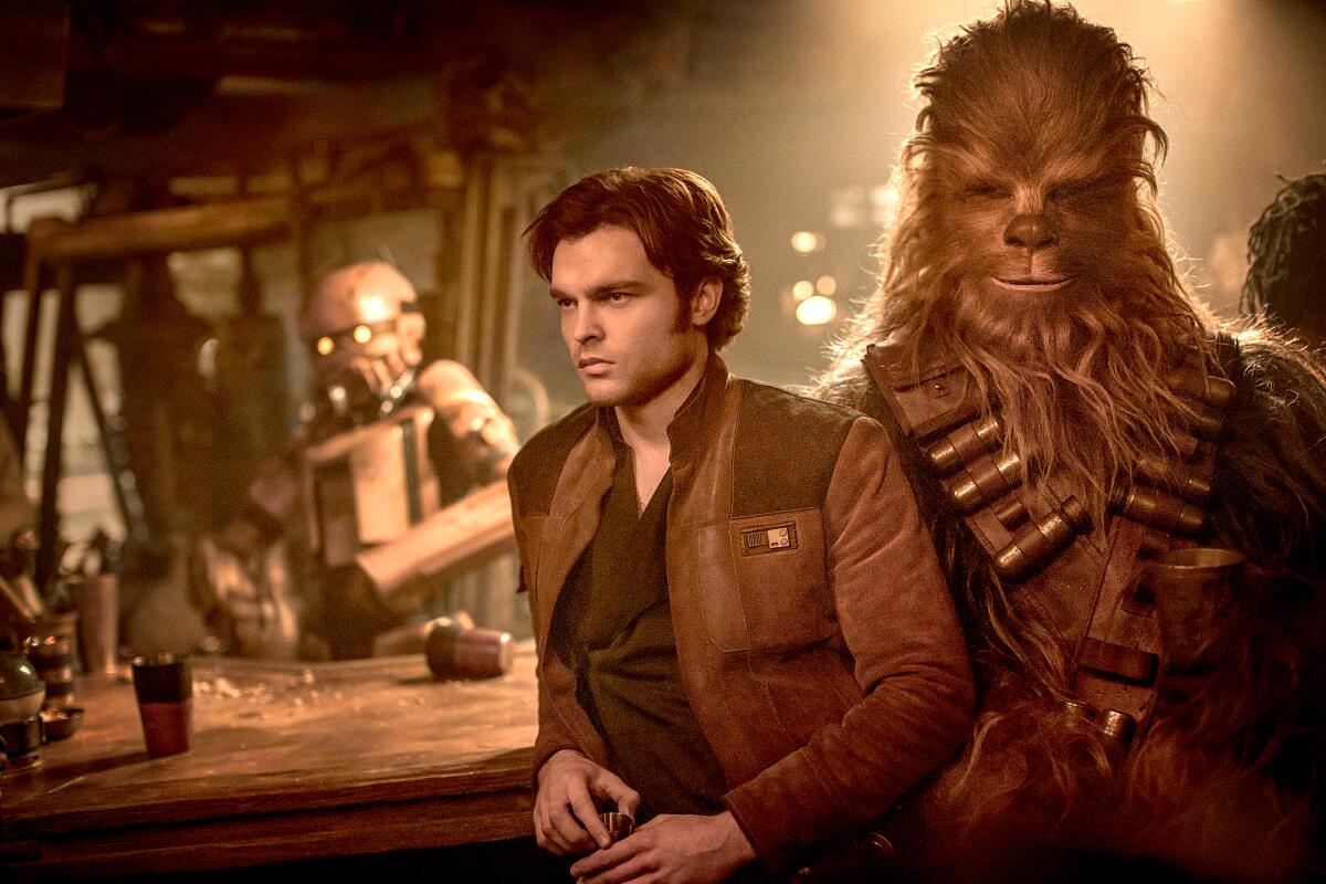 A man in a short brown jacket stands by a Wookiee and leans on a scruffy-looking intergalactic bar
