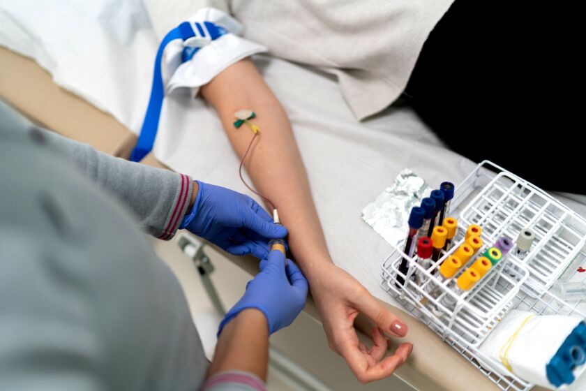 Nurse drawing blood sample from patient vein