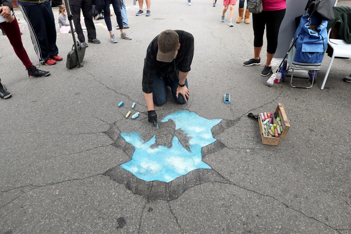 David Zinn draws on the sidewalk on the Promenade on Forest in Laguna Beach during a chalk art demonstration on Saturday.