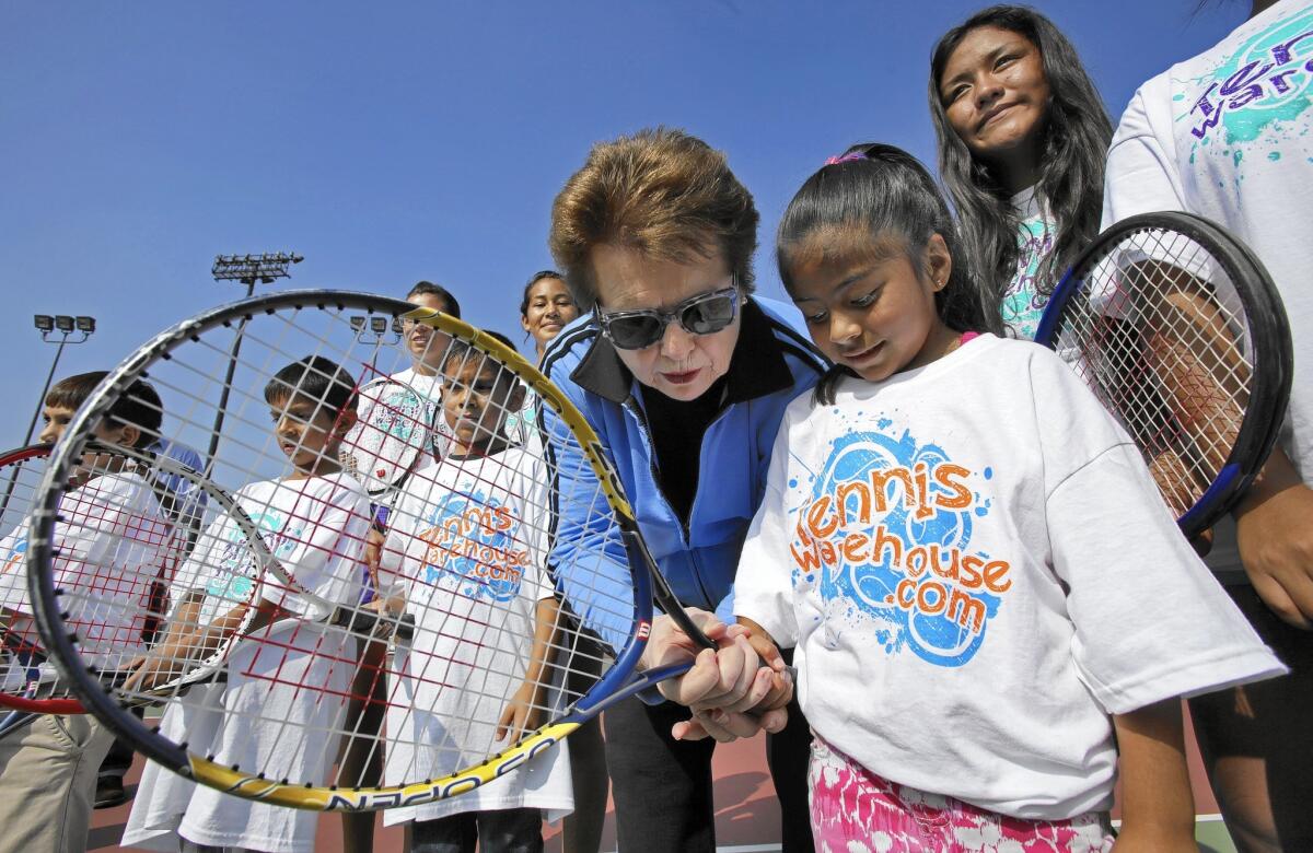 Billie Jean King shows 5-year-old Caroline Escoto how to hold a racquet at a tennis clinic Saturday at Cal State L.A.
