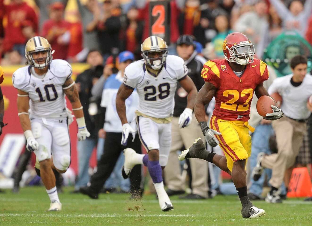 USC tailback Curtis McNeal is off to the races after getting past Washington defenders John Timu, left, and Quinton Richardson on a 79-yard scoring run in the third quarter Saturday.