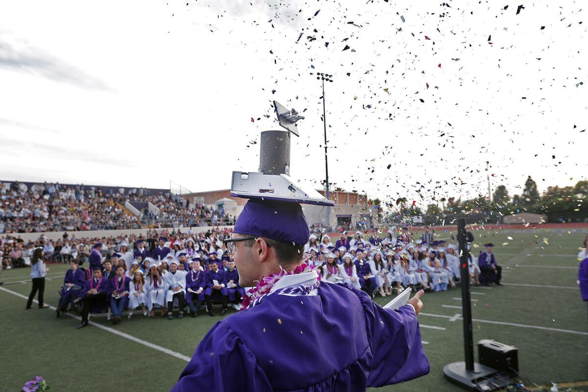 Graduating senior Henry Pruett triggers a burst of confetti from a cone atop his graduation cap as he exits the main stage after graduating from Hoover High School on June 10. Cap decorations are not permitted at some Glendale Unified high schools.
