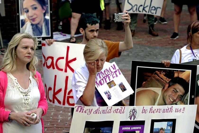 Protesters, including Carol Lorento, center, gather outside a courthouse on Friday, Aug. 2, 2019, in Boston, where a judge was to hear arguments in Massachusetts' lawsuit against Purdue Pharma over its role in the national drug epidemic. Organizers said they wanted to continue to put pressure on the Connecticut pharmaceutical company and the Sackler family that owns it. (AP Photo/Charles Krupa)